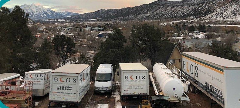 The ECOS fleet of trucks and trailers at the Glenwood-area yard, with snow-covered mountains behind